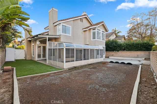 back of property with a yard, a sunroom, and a patio