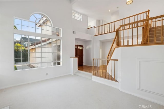 unfurnished living room featuring a towering ceiling and carpet flooring