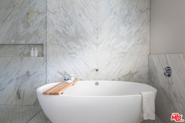 bathroom with a tub and tile walls