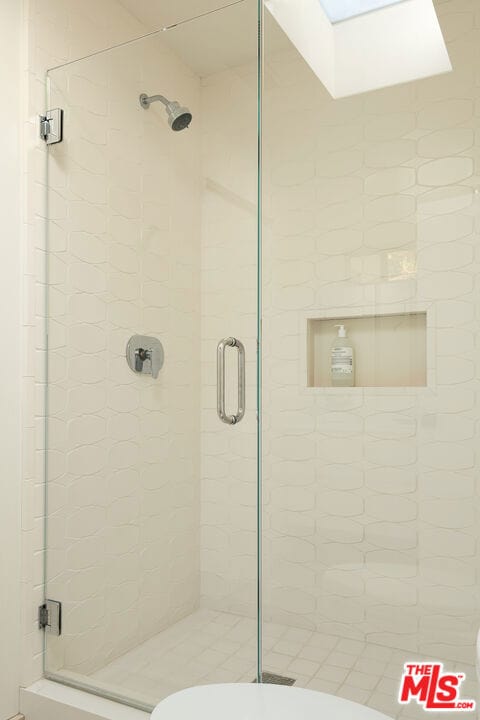 bathroom featuring a shower with shower door and toilet