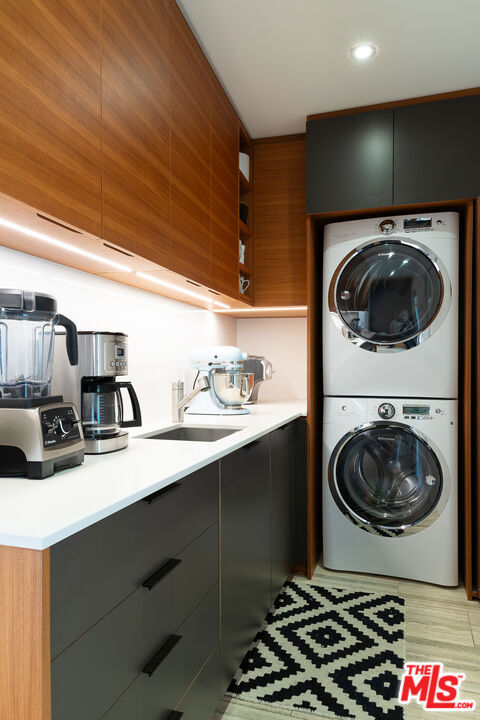 washroom with stacked washer / drying machine and sink