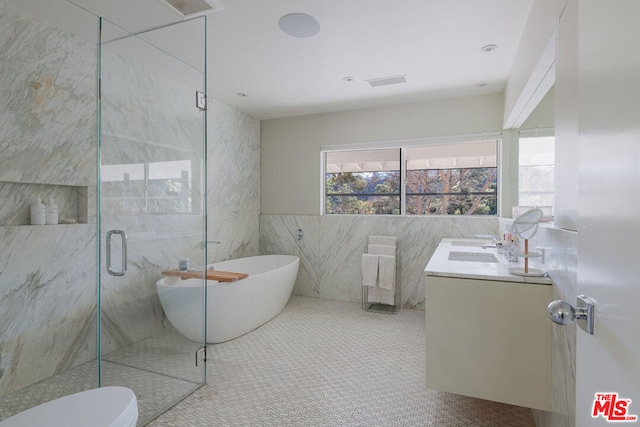 full bathroom with tile walls, tile patterned flooring, separate shower and tub, vanity, and toilet