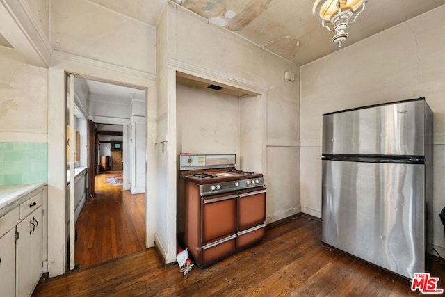 kitchen featuring white cabinets, dark wood-type flooring, range, and stainless steel fridge