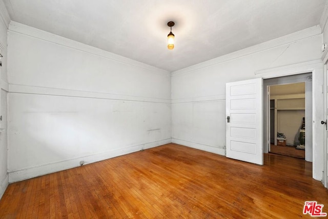 spare room with crown molding and dark wood-type flooring