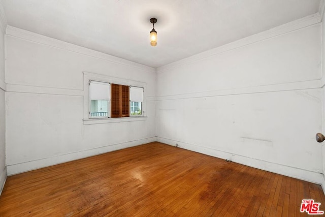 spare room with wood-type flooring and crown molding