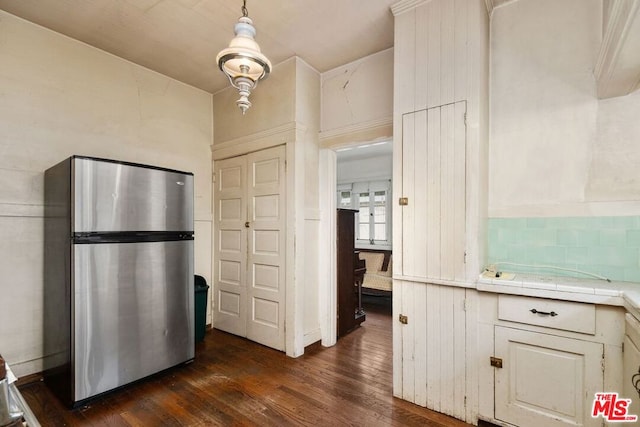 kitchen featuring dark hardwood / wood-style floors, tile countertops, stainless steel refrigerator, decorative light fixtures, and white cabinets