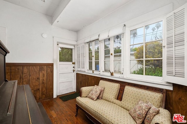 sitting room with dark hardwood / wood-style flooring and wood walls