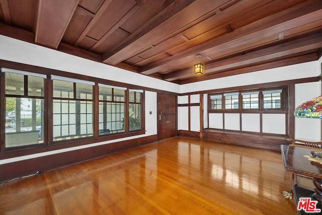 empty room with wood ceiling, wood-type flooring, and beamed ceiling