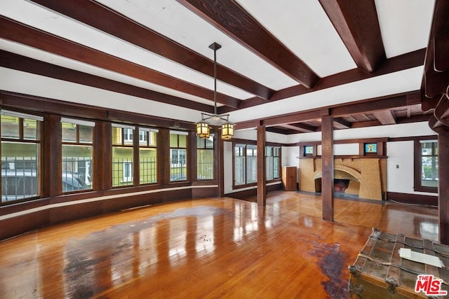 interior space with beam ceiling, a fireplace, and wood-type flooring