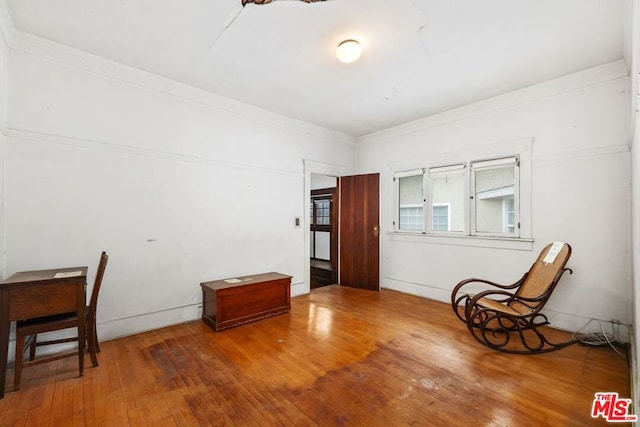 living area featuring wood-type flooring and ornamental molding