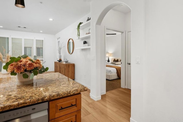 kitchen featuring stainless steel dishwasher, light stone countertops, and light wood-type flooring