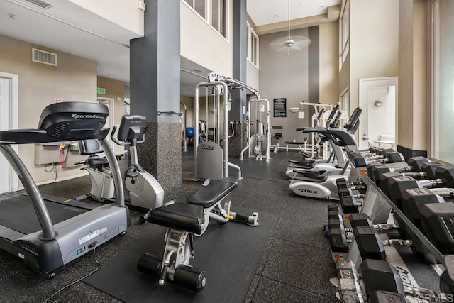 workout area with ceiling fan, visible vents, and a towering ceiling