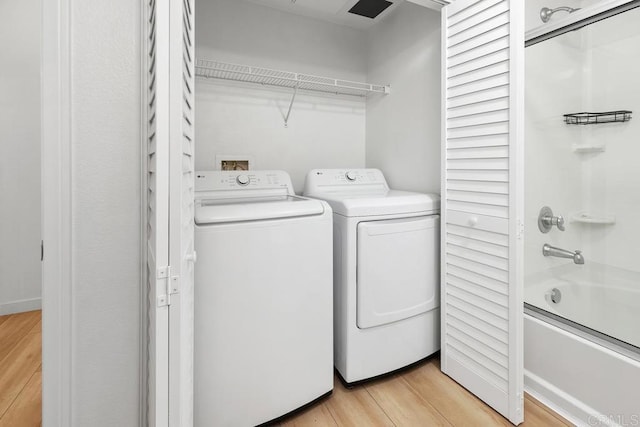 washroom featuring laundry area, washing machine and dryer, and light wood finished floors