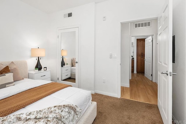 bedroom featuring visible vents, baseboards, and light carpet