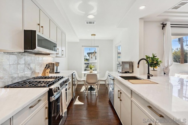 kitchen with pendant lighting, sink, white cabinetry, and appliances with stainless steel finishes