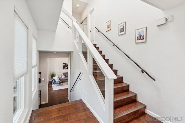 stairway featuring hardwood / wood-style flooring, a high ceiling, and a healthy amount of sunlight