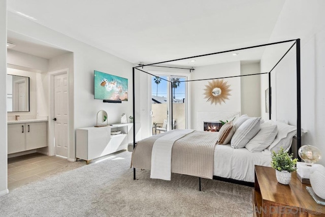 bedroom featuring ensuite bathroom and light carpet