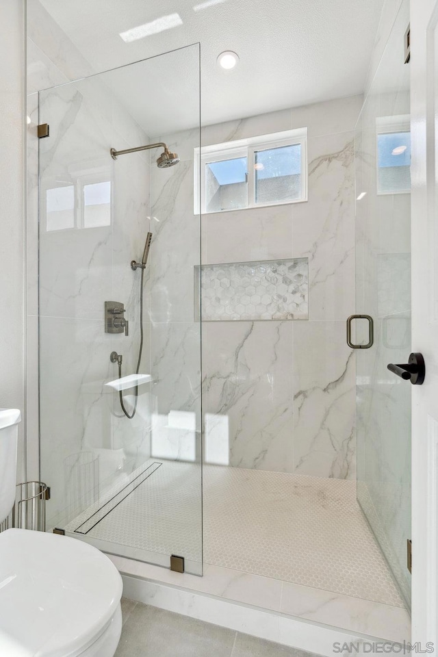 bathroom featuring toilet and a shower with door