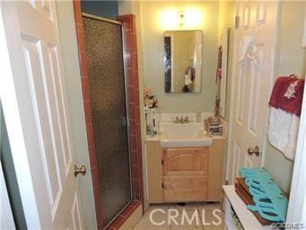 bathroom featuring a shower with shower door and sink