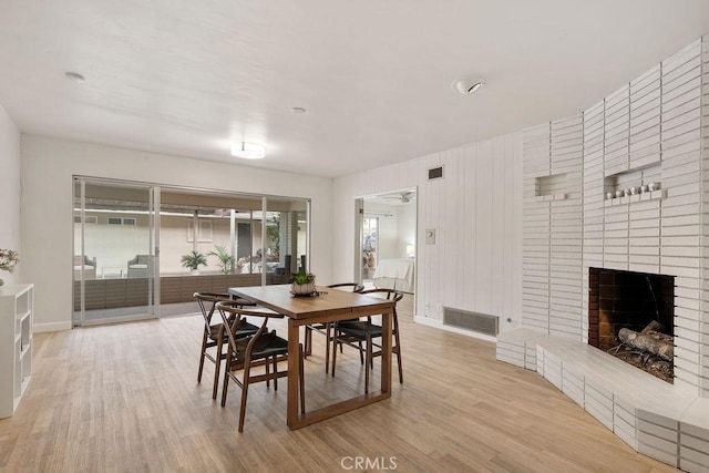 dining room with a brick fireplace and light wood-type flooring