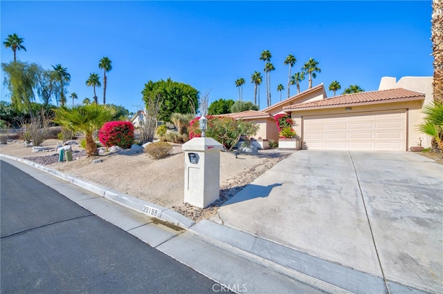 ranch-style home with a garage, a tile roof, concrete driveway, and stucco siding