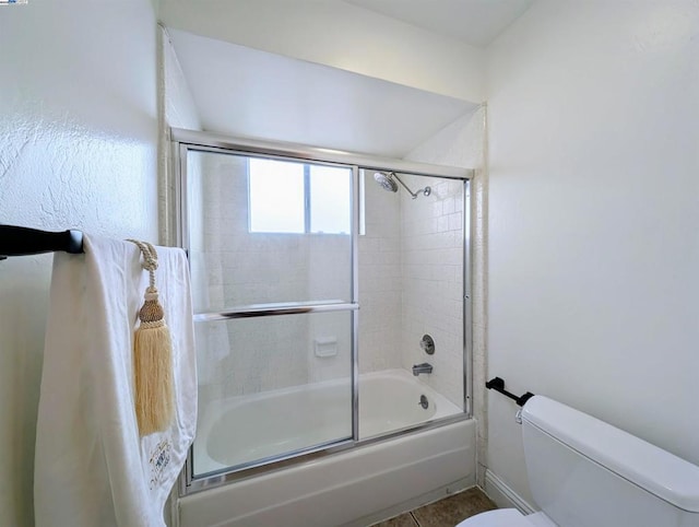 bathroom with tile patterned floors, shower / bath combination with glass door, and toilet