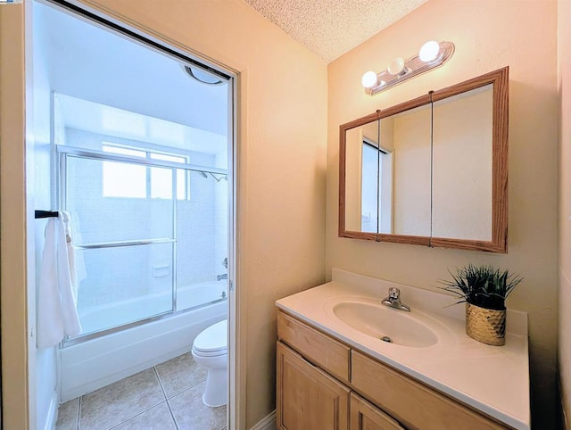 full bathroom featuring combined bath / shower with glass door, vanity, toilet, tile patterned floors, and a textured ceiling