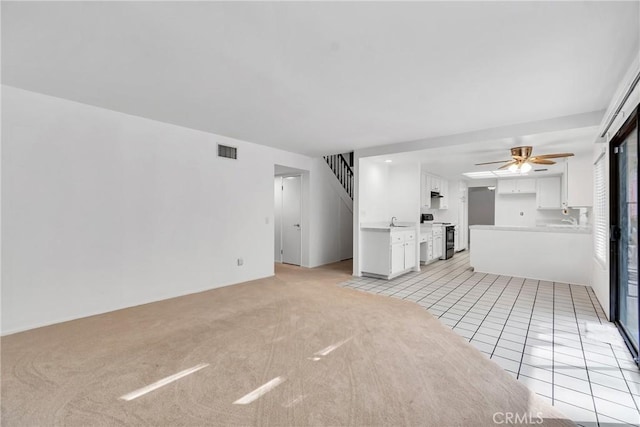 unfurnished living room featuring ceiling fan, sink, and light tile patterned floors