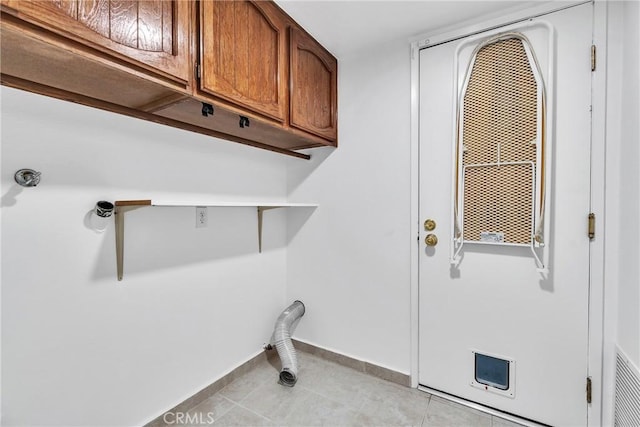 laundry area featuring light tile patterned flooring and cabinets