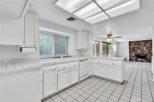 kitchen with white cabinetry, a fireplace, white dishwasher, and kitchen peninsula