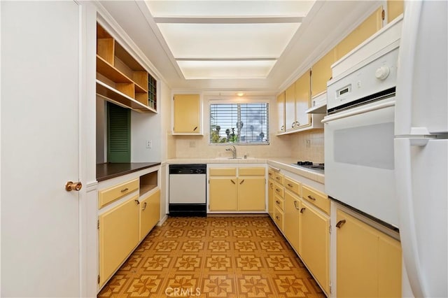 kitchen featuring white appliances, cream cabinets, exhaust hood, decorative backsplash, and a sink