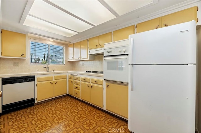 kitchen featuring white appliances, under cabinet range hood, cream cabinets, tile counters, and backsplash