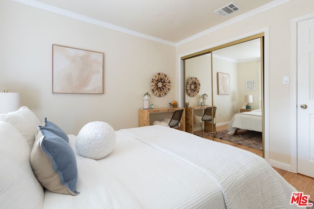 bedroom with crown molding, light wood-type flooring, and a closet