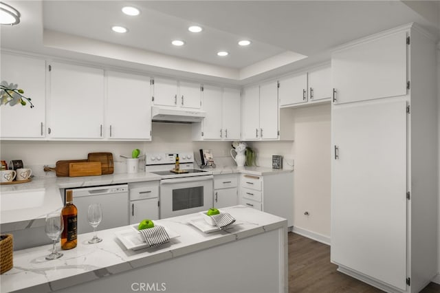 kitchen with white cabinetry, white appliances, dark wood-type flooring, and a tray ceiling