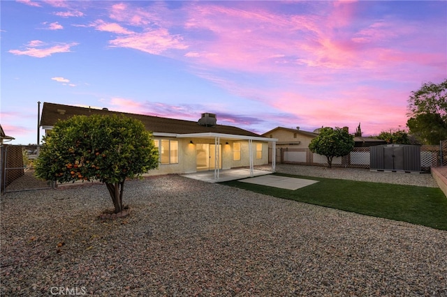 back house at dusk featuring a patio area