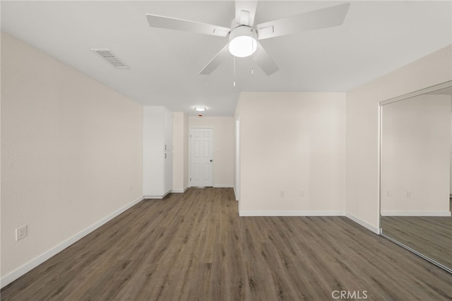 empty room featuring dark wood-type flooring and ceiling fan