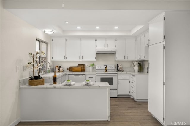 kitchen with white appliances, kitchen peninsula, and white cabinets