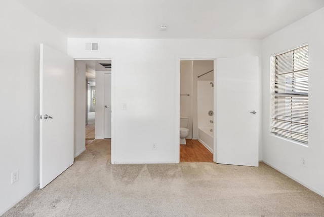 unfurnished bedroom with light carpet and ensuite bathroom