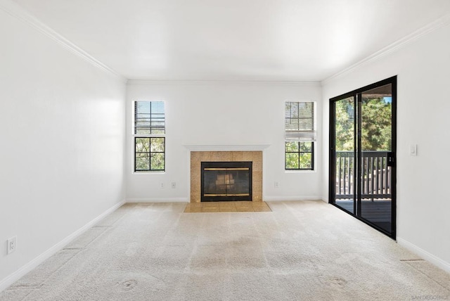 unfurnished living room featuring a tile fireplace, ornamental molding, and light carpet