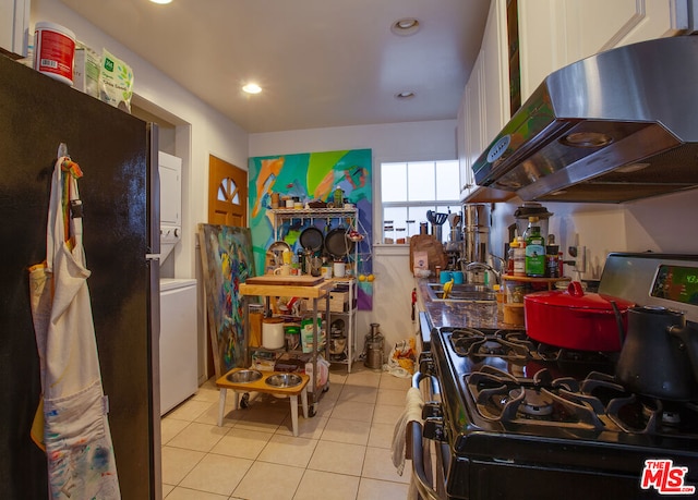 kitchen featuring sink, white cabinetry, stainless steel appliances, stacked washing maching and dryer, and range hood