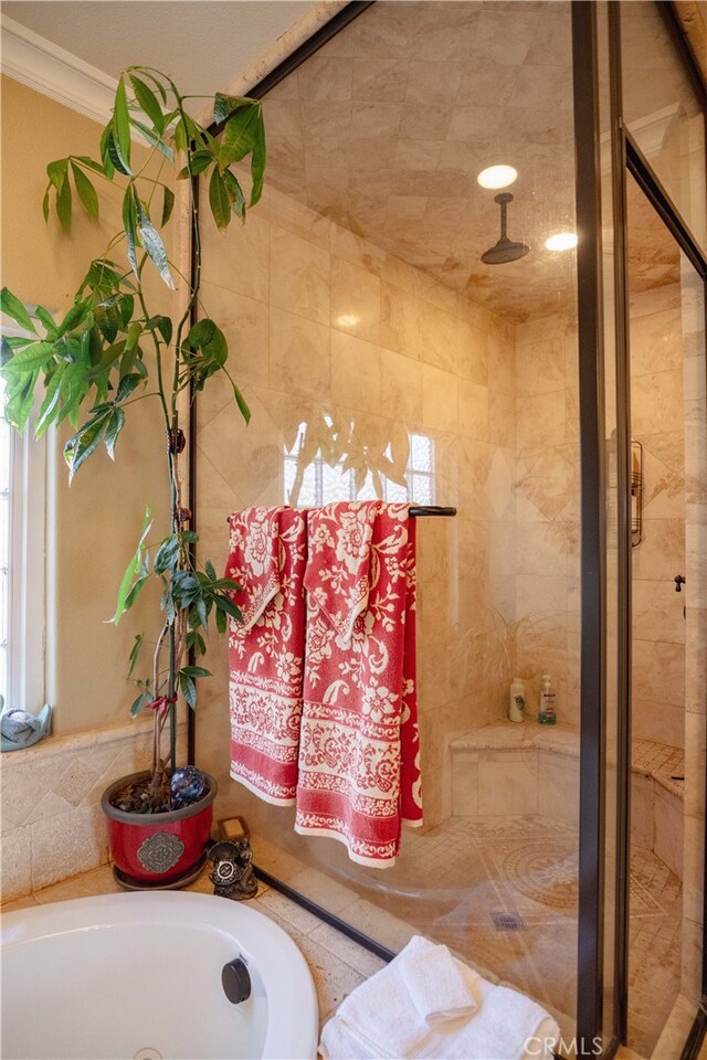 bathroom with ornamental molding and shower with separate bathtub