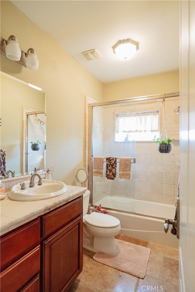 full bathroom featuring toilet, vanity, and bath / shower combo with glass door