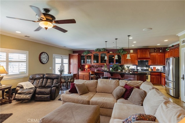 carpeted living room with crown molding and ceiling fan