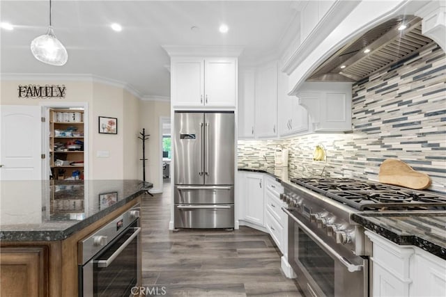 kitchen with custom exhaust hood, white cabinets, premium appliances, and dark stone counters