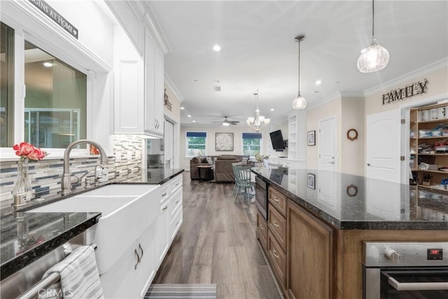 kitchen featuring a center island, dark stone countertops, white cabinets, and decorative light fixtures