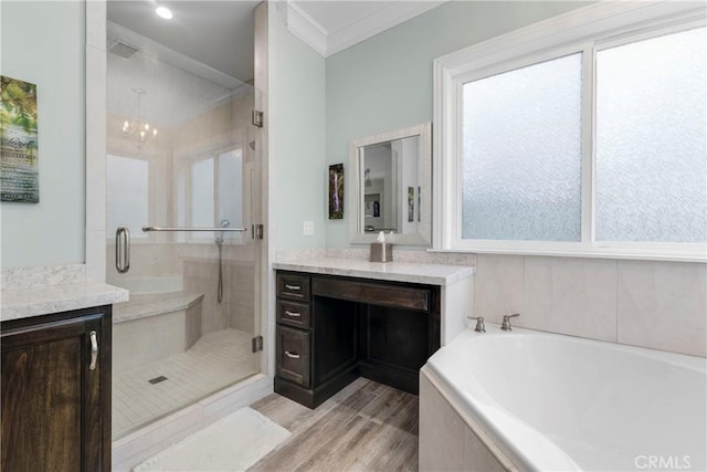 bathroom featuring shower with separate bathtub, a chandelier, hardwood / wood-style flooring, vanity, and crown molding