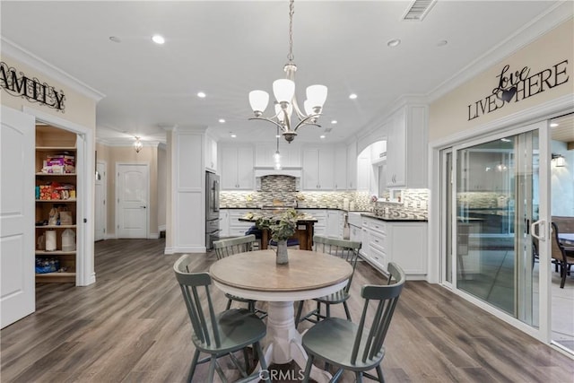 dining space featuring ornamental molding, dark hardwood / wood-style floors, sink, and an inviting chandelier