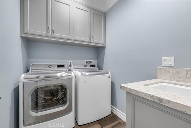 washroom featuring cabinets, wood-type flooring, sink, and washing machine and dryer