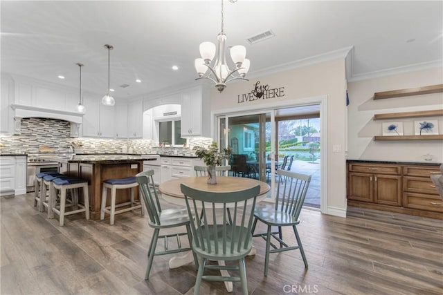 dining area with crown molding, a chandelier, and hardwood / wood-style flooring