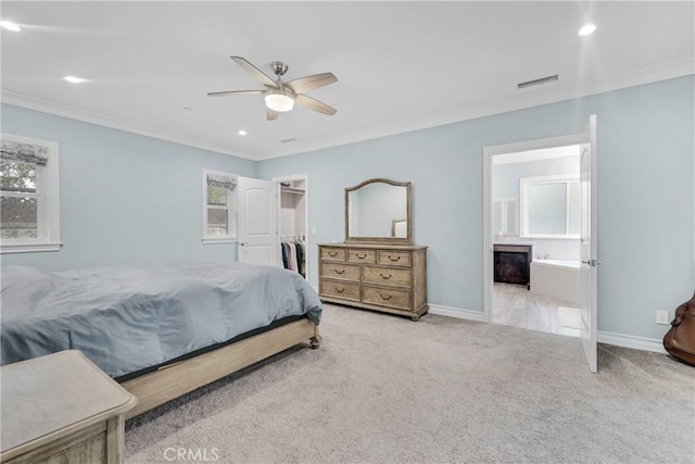 bedroom with a walk in closet, ornamental molding, light colored carpet, and ensuite bathroom